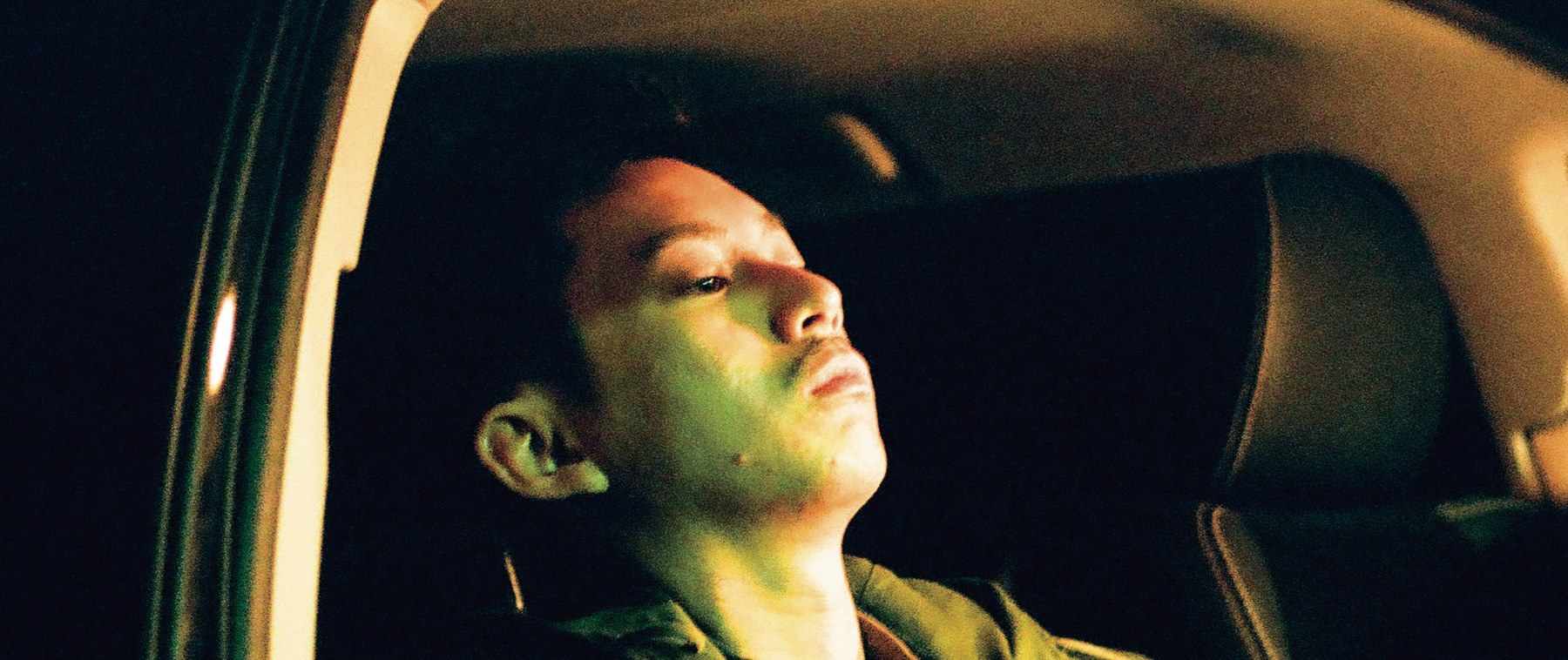 映画「ただ、そばにいる。」より。夜の車内、緑の光に照らされて上を見上げる男